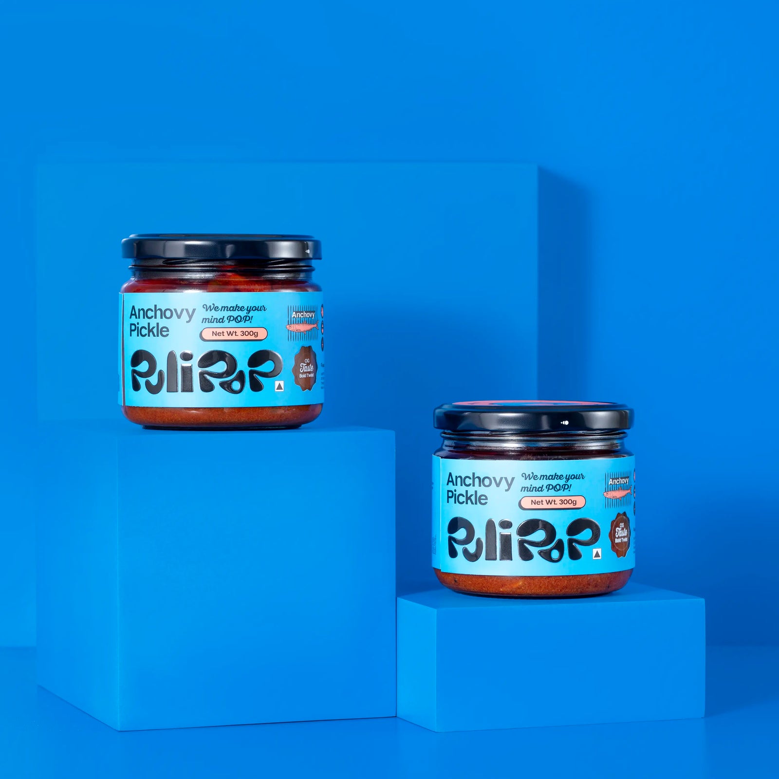 Two jars of Anchovy Pickle by PuliPOP on stepped blue pedestals