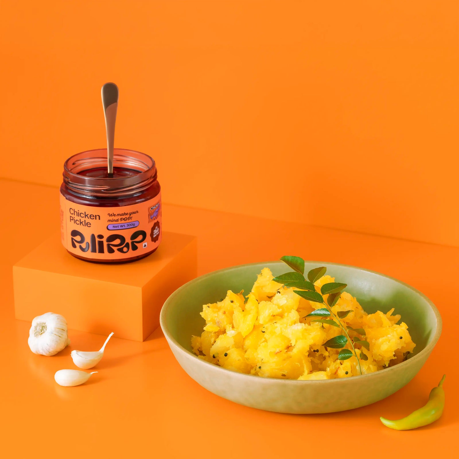 Chicken Pickle by PuliPOP with a bowl of upma, garlic cloves and green chilli